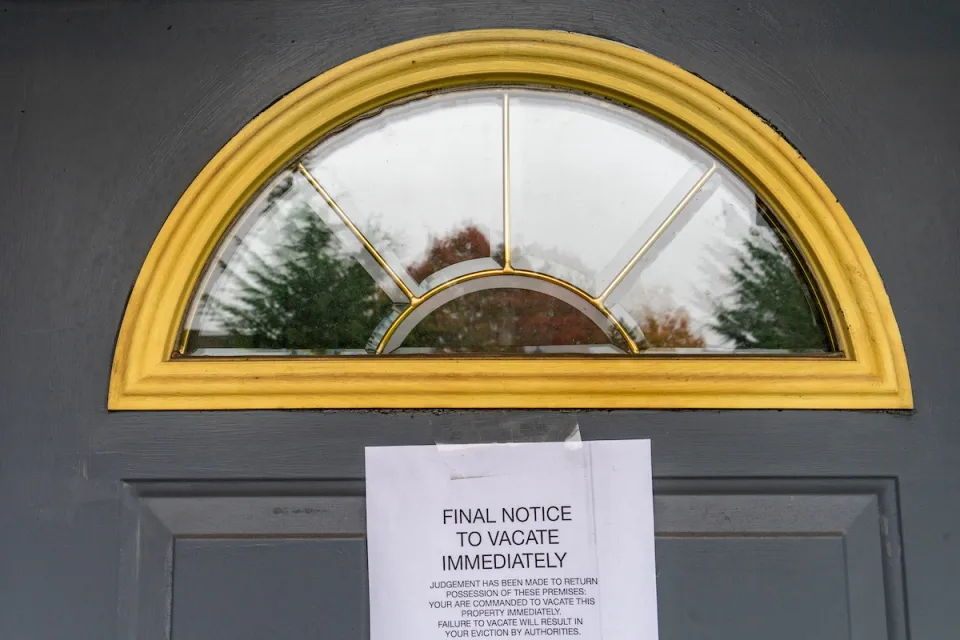 Eviction notice taped to dark grey door with arched window at top.